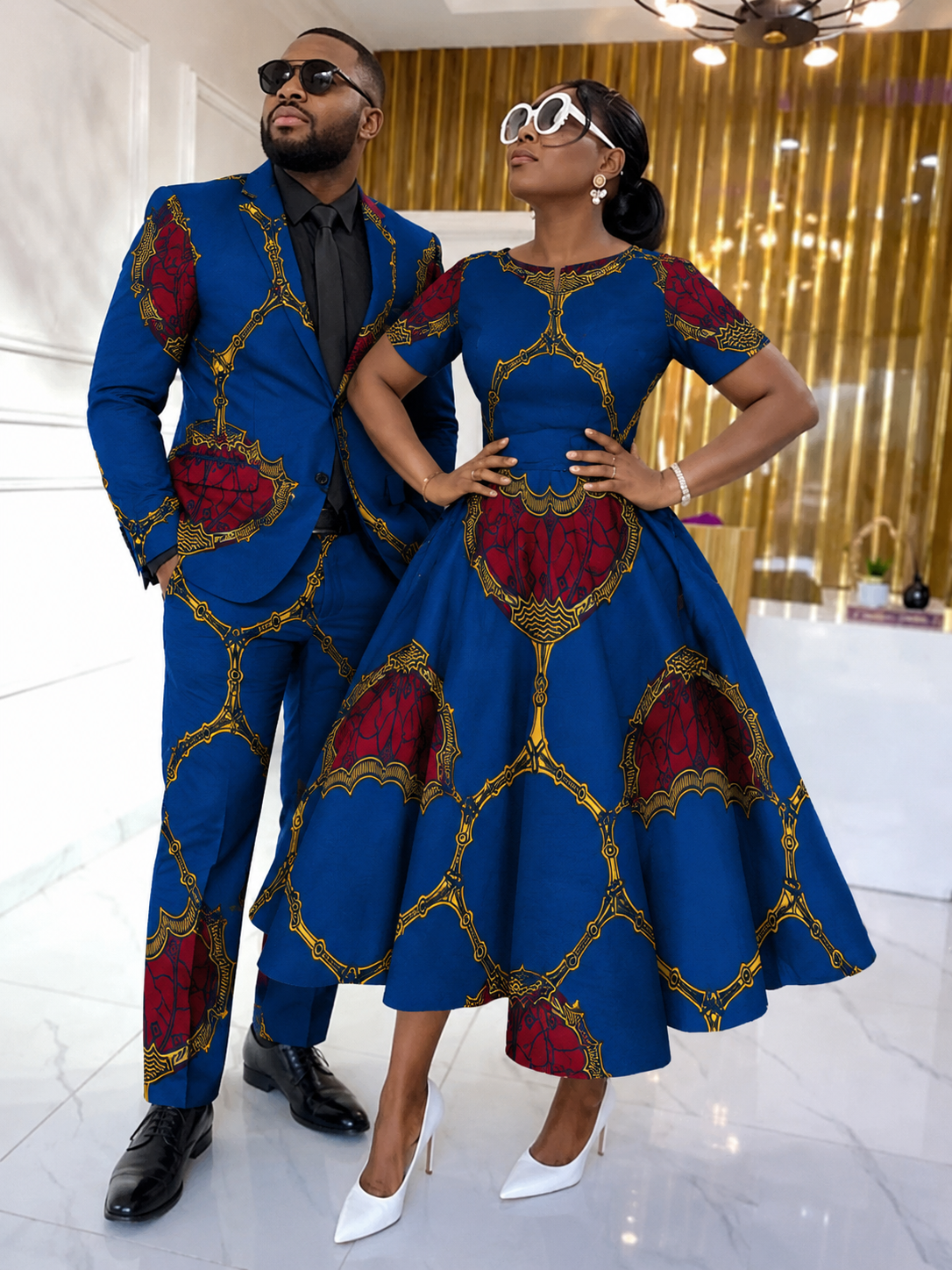 Couple styled in royal blue and crimson Ankara — man in tailored suit, woman in flare dress