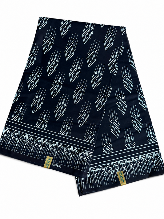 Couple wearing matching black and white geometric diamond African wax print outfits — woman in off-shoulder mermaid dress, man in printed trousers and white shirt