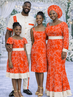 Family of four wearing coordinated orange abstract map print African outfits at a wedding celebration