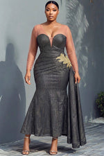 Woman wearing black and gold metallic stripe mermaid gown with sheer nude illusion sweetheart neckline, sheer long sleeves, ruched diagonal skirt, gold lace floral appliqué at hip and sweeping side cape train