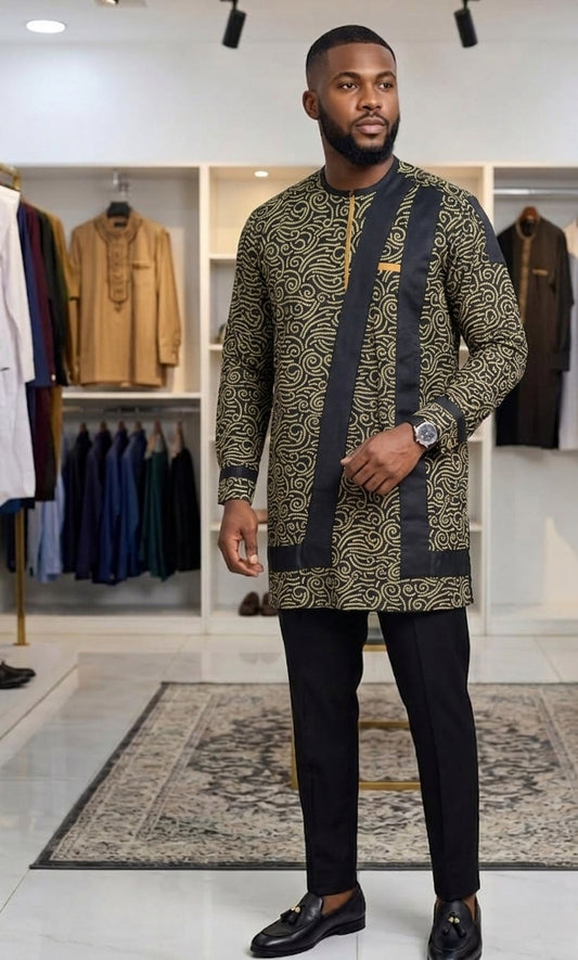 Man wearing a gold swirl Ankara Senator long shirt with black contrast placket, paired with black trousers and loafers