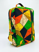 Front angle view of Ankara geometric kaleidoscope patchwork backpack in green, orange, yellow and black triangle print with Ankara top handle