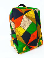 Three-quarter view of Ankara geometric patchwork backpack in green, orange and yellow kaleidoscope print with side zip pocket and House of Prints branded tag