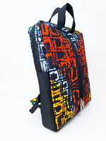 Side view of Ankara print laptop backpack in orange, red and yellow abstract batik pattern with dual black top handles and side zip pocket