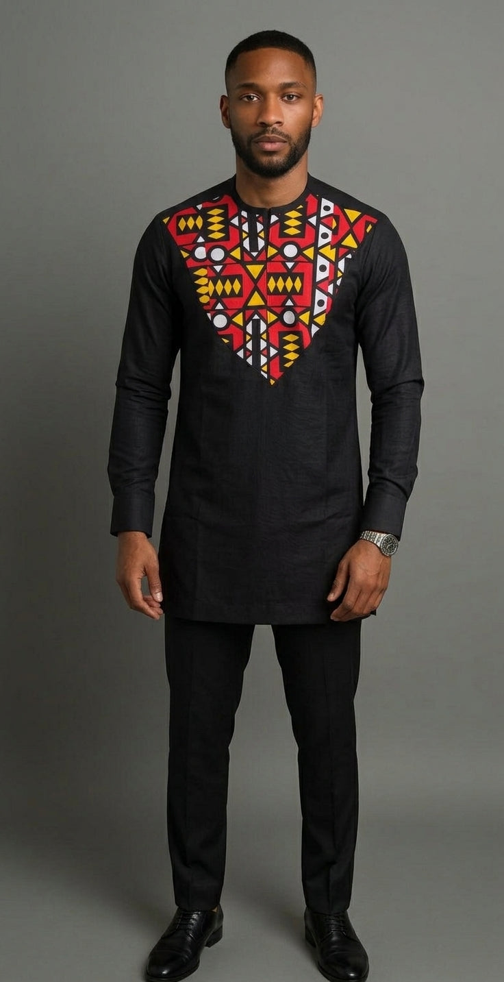 Man wearing a black Nigerian Senator two-piece with bold red, yellow and white geometric Ankara V-yoke panel and black trousers