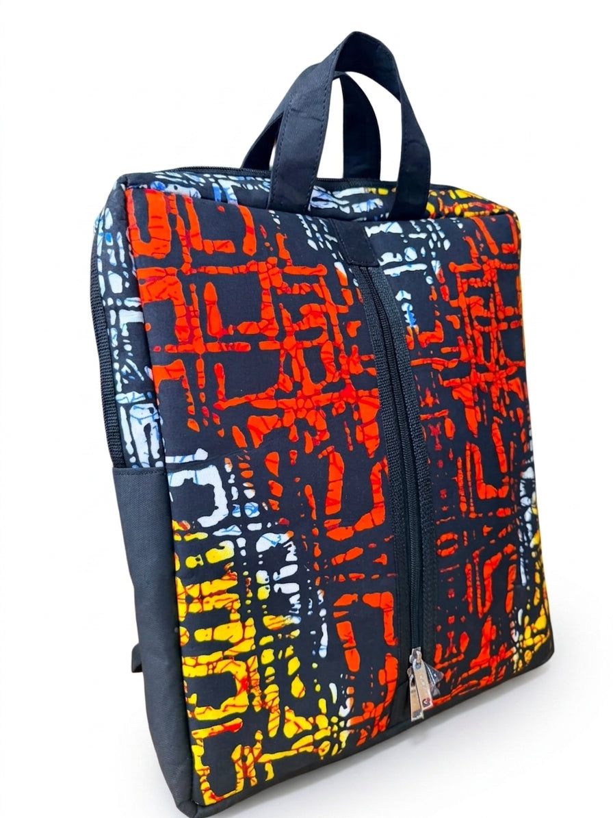 Angled front view of Ankara print laptop backpack showing full abstract batik print, front zip pocket and padded backpack straps