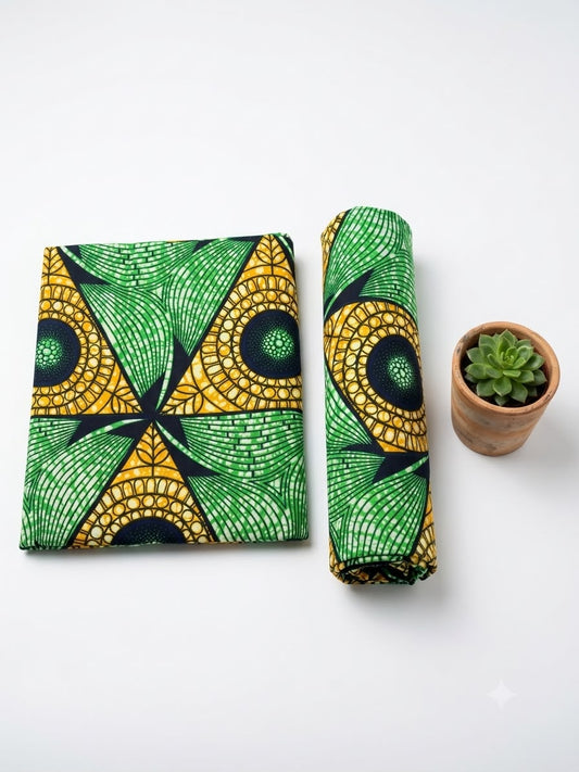 Green and gold geometric fan Ankara African print cotton fabric, folded and rolled with a small succulent plant
